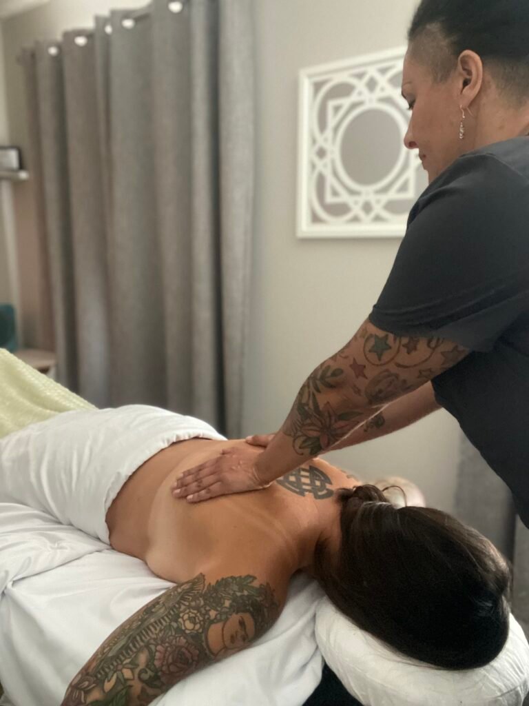 Lynn of Lynn Does Massage LLC giving a person lying on a massage table a massage.